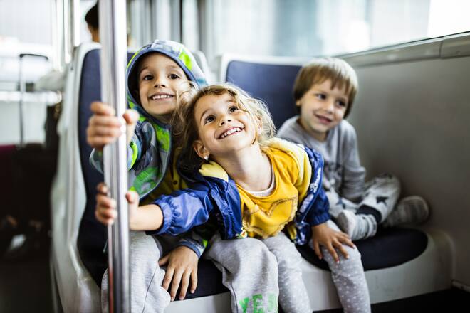 Group of happy kids having fun while driving in shuttle bus.