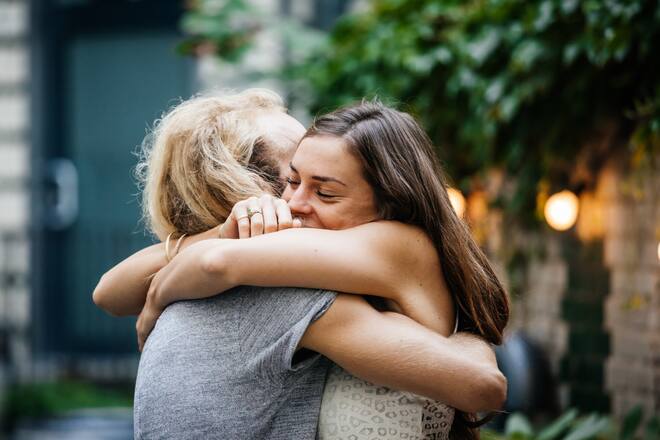 A young couple lovingly embrace each other during a meetup and barbecue with friends.