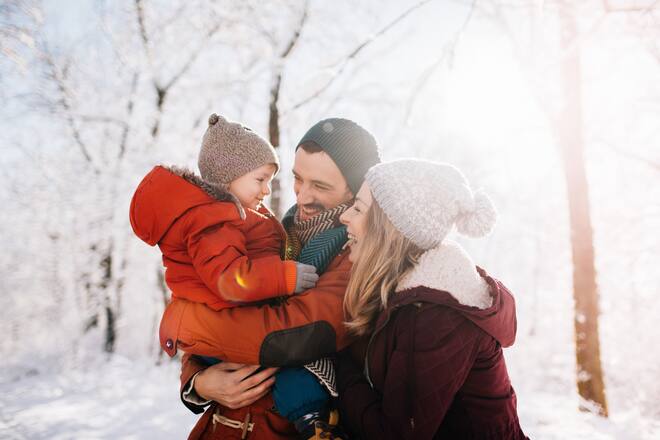Photo of a cheerful young family, being playful outdoors in nature covered in snow