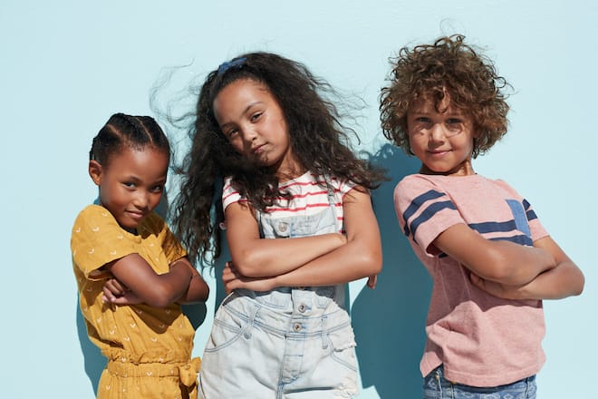 Children having joyful interaction, shot on a blue solid background on the beach in full sun