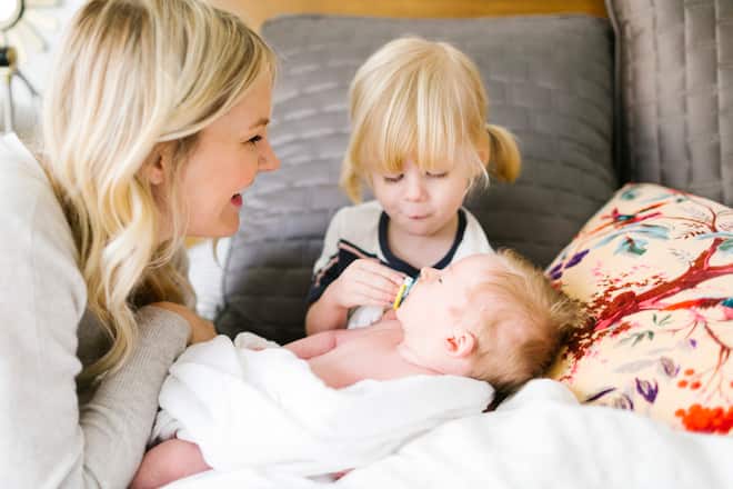 Fröhliche Mutter mit Baby und kleiner Tochter auf Bett