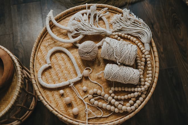 Top view of macrame heart shape decor and cotton threads on the wicker table. Flat lay. Selective focus.