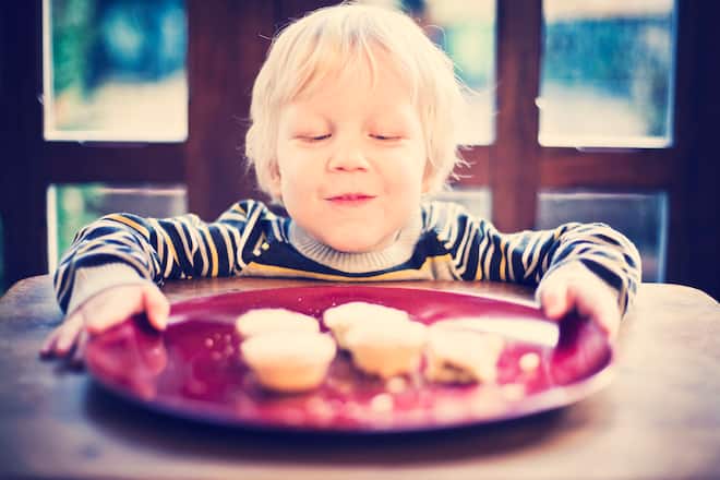 Happy smiling little boy looking at plate of festive mince pies.