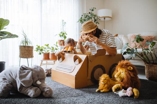 Vater und Tochter machen Safari im Wohnzimmer mit gebasteltem Auto
