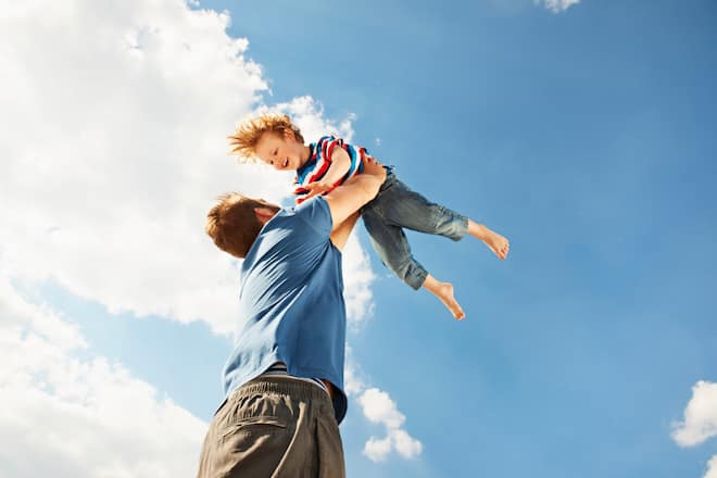 Father tossing son in air, son smiling