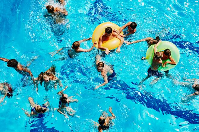 Group of kids playing together in outdoor pool overhead view