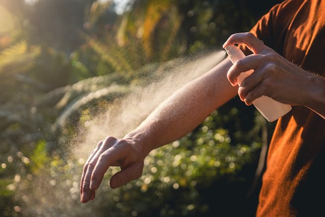 Man while applying insect repellent on his hand. Prevention against mosquito bite in tropical destination.