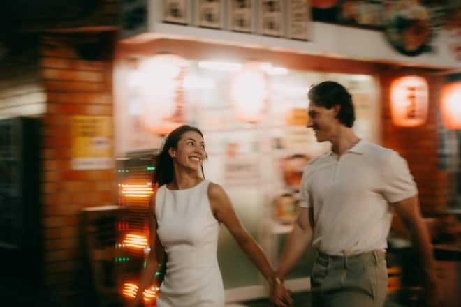 Young couple having a great time in Tokyo backstreet alley with izakaya at night