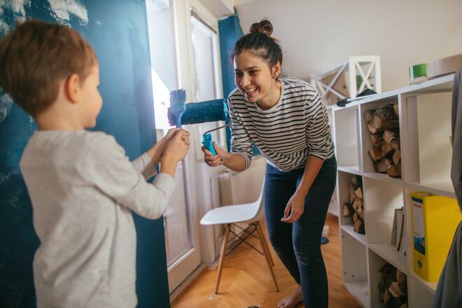 Mutter und Sohn streichen eine Wand.