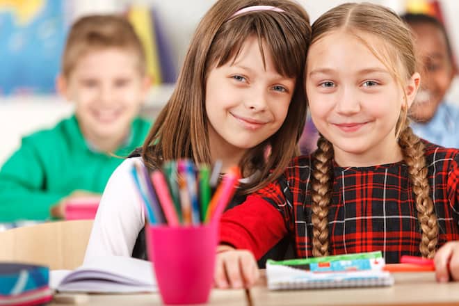 Zwei glückliche Mädchen im Schulzimmer