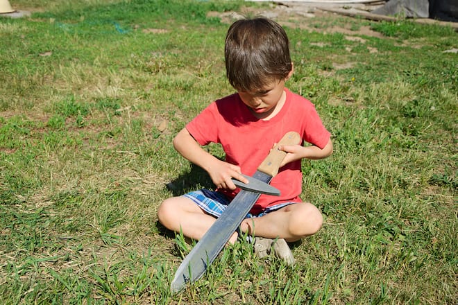 Boy learning in machete edge blade sharpening