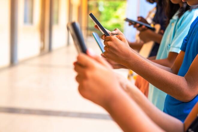 Close up shot, group of children hands busy using smartphone at school corridor - concept of social media, playing games, technology and education.