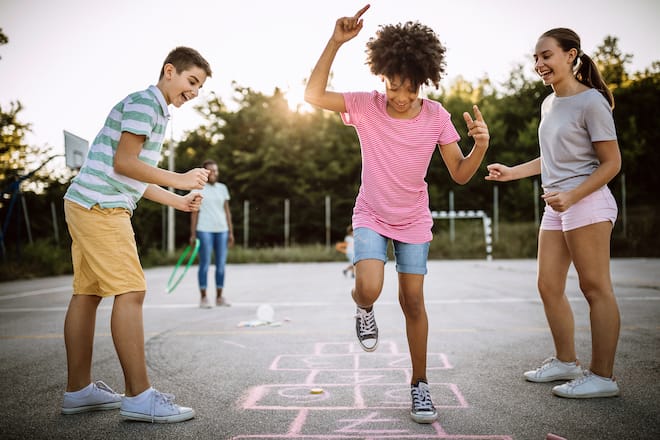 Ältere Kinder spielen Himmel und Hölle auf dem Pausenplatz