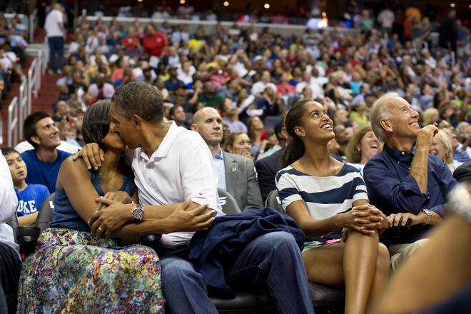 WASHINGTON, DC - JULY 16: In this handout image provided by the White House, U.S. President Barack Obama kisses First Lady Michelle Obama for the "Kiss Cam" while Vice President Joe Biden and Malia Obama look up at the jumbotron, during the U.S. Men's Olympic basketball team's game against Brazil at the Verizon Center on July 16, 2012 in Washington, D.C. (Photo by Pete Souza/White House Photo via Getty Images)