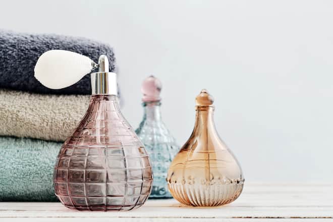 Vintage antique bottles with perfume and stack of towels on blue background