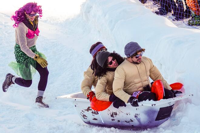people in the snow on a bath tub