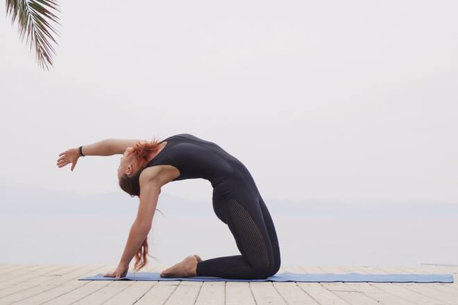 Handsome female doing hatha yoga asana at sea on foggy sunrise 1