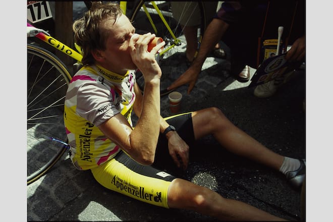 Beat Breu sitzt nach einer Tour de Suisse Etappe 1991 erschöpft am Boden und trinkt.