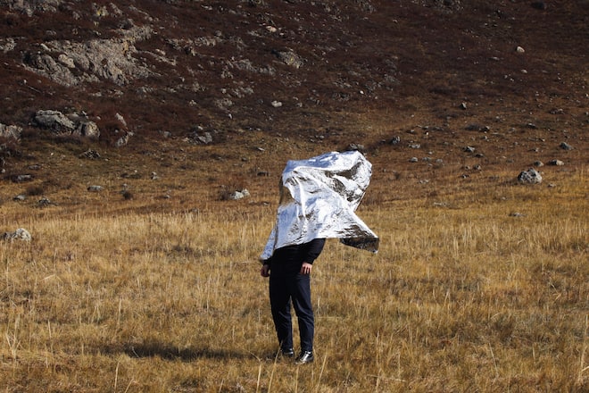 Man covered with silver foil against field