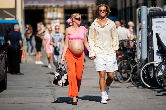 COPENHAGEN, DENMARK - AUGUST 11: Hanna Stefansson wearing pink cropped top, orange trousers and Frederik Darre wearing white shorts, yellow shirt are seen outside Samsøe & Samsøe during Copenhagen Fashion Week Spring/Summer 2021 on August 11, 2020 in Copenhagen, Denmark. (Photo by Christian Vierig/Getty Images)