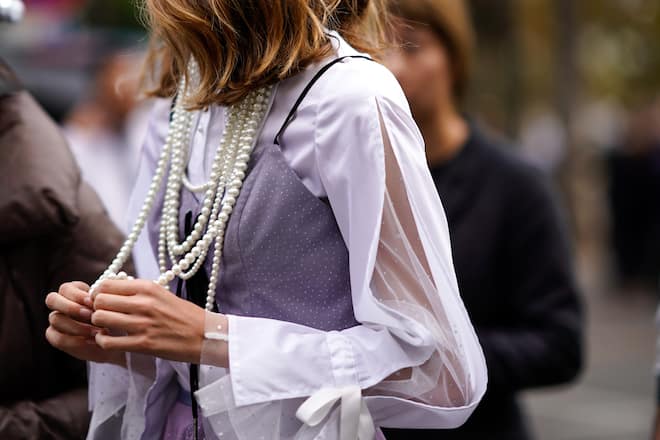 PARIS, FRANCE - SEPTEMBER 30:  A guest wears a pearl necklace, a pink lace dress, outside Akris, during Paris Fashion Week Womenswear Spring/Summer 2019, on September 30, 2018 in Paris, France.  (Photo by Edward Berthelot/Getty Images)