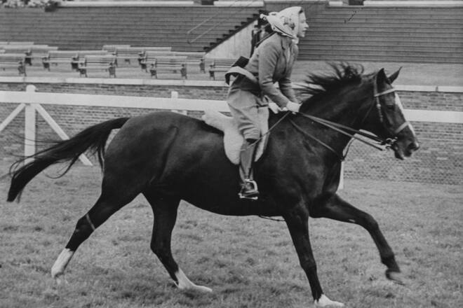 Queen Elizabeth II wears a fawn coloured jacket, breeches and head scarf as she gallops on a black horse along the course at Ascot Racecourse in England on June 16th 1960. (Photo by Paul Popper/Popperfoto via Getty Images/Getty Images)