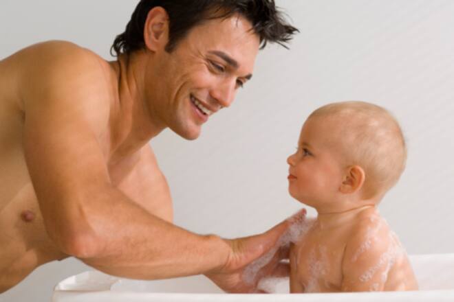Ein fröhlicher Vater badet sein Baby
