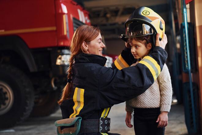 Feuerwehrfrau zieht Mädchen Helm an