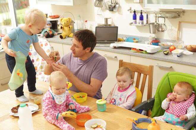 Vater mit vier Babys und Kleinkindern am Esstisch