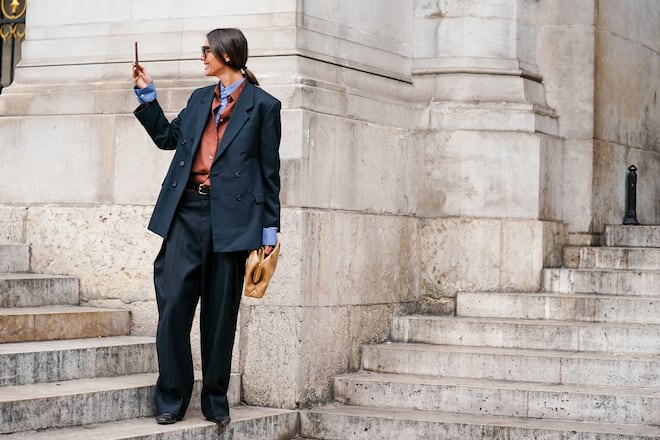 PARIS, FRANCE - SEPTEMBER 30: Julie Pelipas wears sunglasses, a blue shirt, a rust-color shirt, a dark grey oversized double-breasted jacket, dark grey oversized wide-legs full-length pants, a black belt, a camel clutch, black shoes, outside Stella McCartney , during Paris Fashion Week - Womenswear Spring Summer 2020, on September 30, 2019 in Paris, France. (Photo by Edward Berthelot/Getty Images)