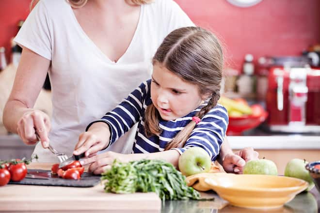 Mädchen rüstet Gemüse mit ihrer Mama
