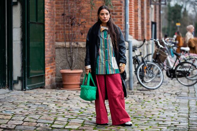 COPENHAGEN, DENMARK - JANUARY 28: A guest is seen wearing green bag, red wide leg pants, striped button shirt, black coat outside Mykke Hofmann on Day 1 during Copenhagen Fashion Week Autumn/Winter 2020 on January 28, 2020 in Copenhagen, Denmark. (Photo by Christian Vierig/Getty Images)