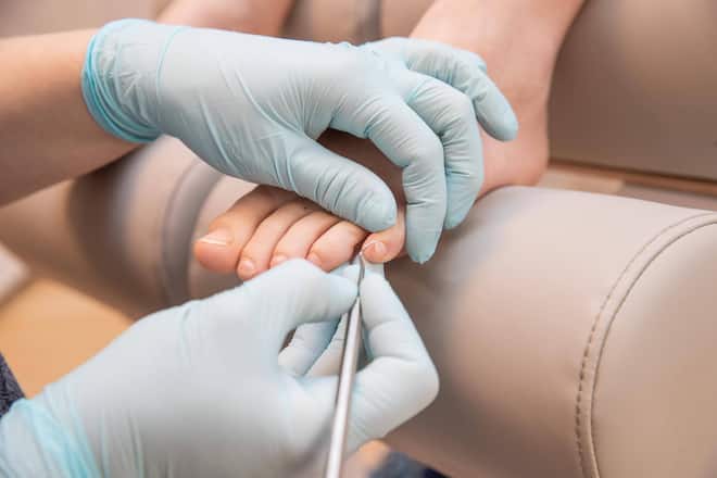 Podologin pflegt Füsse einer Patientin