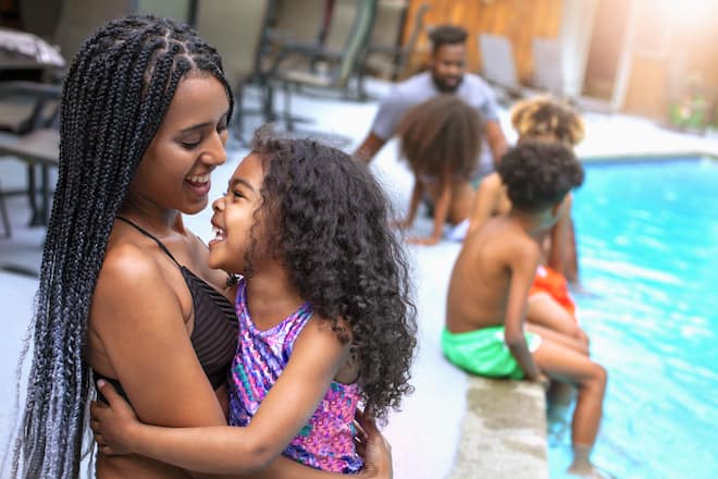 Happy African-American family resting at backyard swimming pool