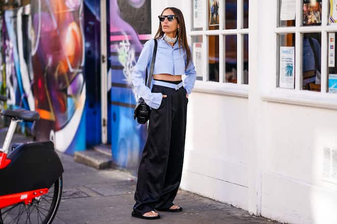 LONDON, ENGLAND - SEPTEMBER 14: Chloe Harrouche wears sunglasses, earrings, a beaded choker, a pale blue cropped shirt, black flare pants, a bag, sandals, during London Fashion Week September 2019 on September 14, 2019 in London, England. (Photo by Edward Berthelot/Getty Images)