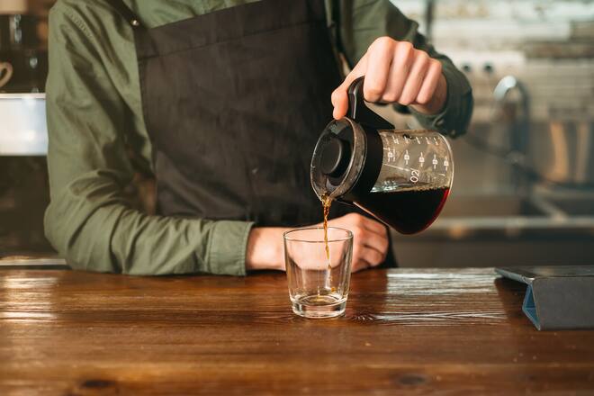 Barman pours coffee in a glass.
