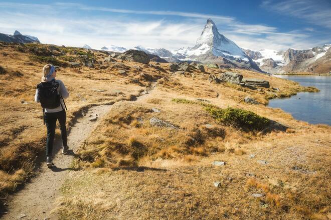 A female hiker explores a lake under the Matterhorn in Zermatt, Switzerland.