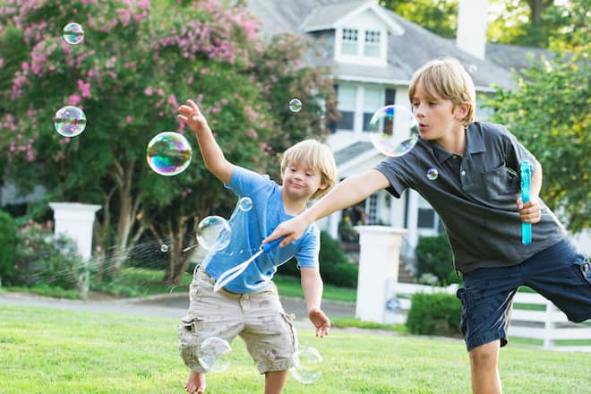 Bub mit Down-Syndrom und sein Bruder spielen mit Seifenblasen
