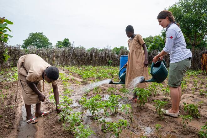 Dominik Gisin hilft die beiden Schülerinnen (12) beim Wasserholen und -geben für den Schülergarten im Dorf Kpakparakpade. Province Centrale, Togo, SRK, Schweizerisches Rotes Kreuz. Foto: Bernard van Dierendonck