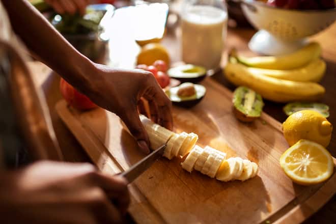 Close up of a young woman making a healthy meal at home in her kitchen using various fruits and vegetables