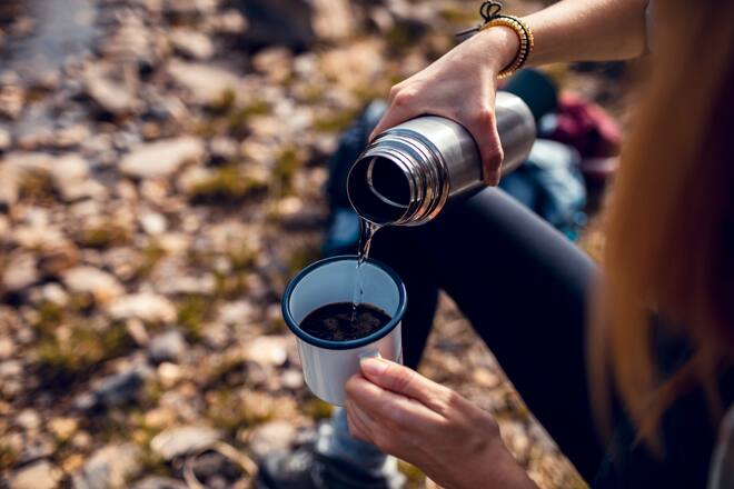 Close up of a young woman having a cup of coffee while taking a break from hiking