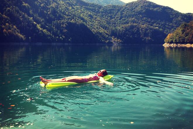 A woman in bikini floating on an air mattress on a lake in Italy.