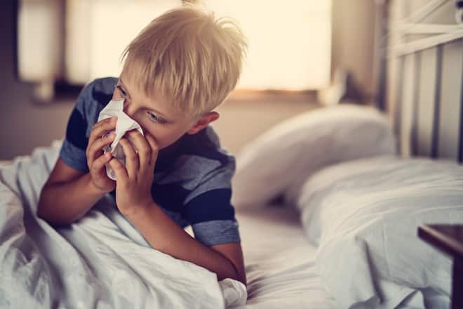 Portrait of sick little boy aged 8 lying in bed.