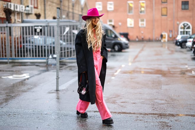 COPENHAGEN, DENMARK - FEBRUARY 01: Emili Sindlev wearing a pink shirt and matching pants, a black coat, black boots, a pink cowboy hat and a bag by Fendi is seen at the RABENS SALONER fashion show on February 1, 2022 in Copenhagen, Denmark. (Photo by Streetstyleshooters/Getty Images)