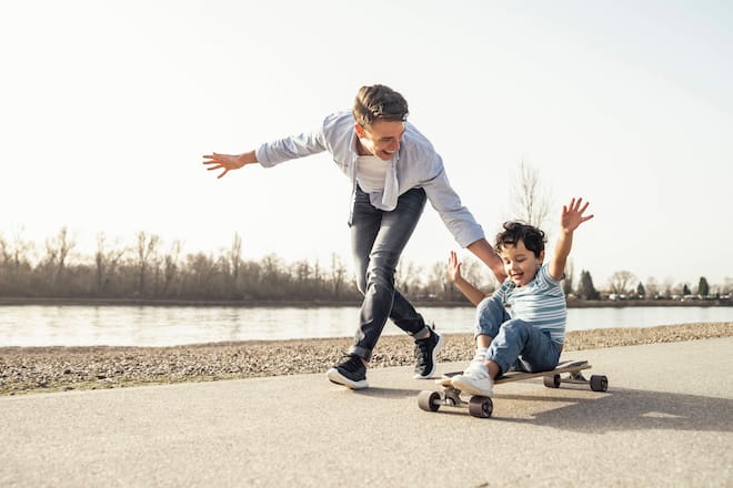 Young man playing with sitting on skateboard during sunny day model released Symbolfoto UUF23050