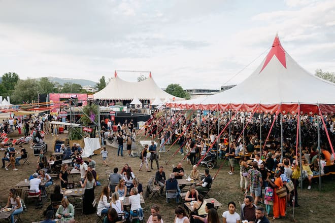 a festival scene with many people under tents