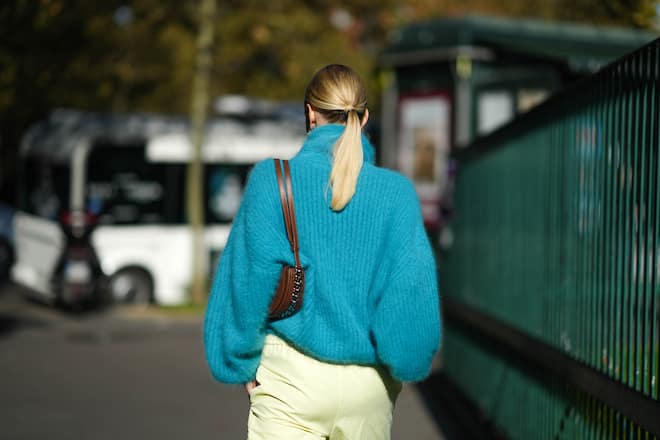 PARIS, FRANCE - OCTOBER 04: Leonie Hanne wears a gold and silver large pendant earrings, a blue fluffy turtleneck oversized pullover, a brown shiny leather with a chain shoulder bag form Stella McCartney, pale yellow high waist cargo pants, outside the Stella McCartney show, during Paris Fashion Week - Womenswear Spring Summer 2022, on October 04, 2021 in Paris, France. (Photo by Edward Berthelot/Getty Images)