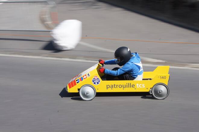 eine person fährt in einer gelben seifenkiste