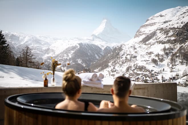 Impressionen aus dem Spa & Wellness Bereich des CERVO Mountain Resort in Zermatt. Paar im Whirlpool auf der Terrasse geniesst die Sicht auf's Matterhorn.