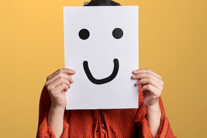 Seine wahren Gefühle hinter einem Lächeln zu verbergen, ist typisch für toxisch positive Menschen.